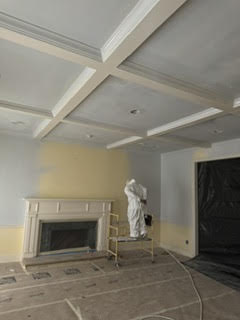 Painter finishing coffered ceiling and fireplace wall